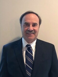 A man in suit and tie smiling for the camera.