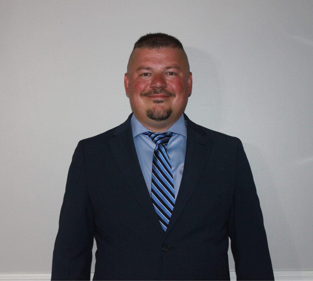 A man in a suit and tie standing next to a wall.